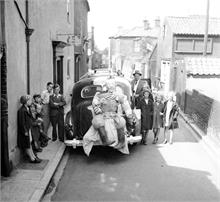 Children and figure attached to car on Vicarage Street.