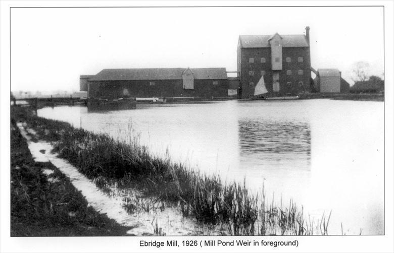 Photograph. Ebridge Mill beyond its Mill Pond. Mill Pond Weir in left foreground (North Walsham Archive).
