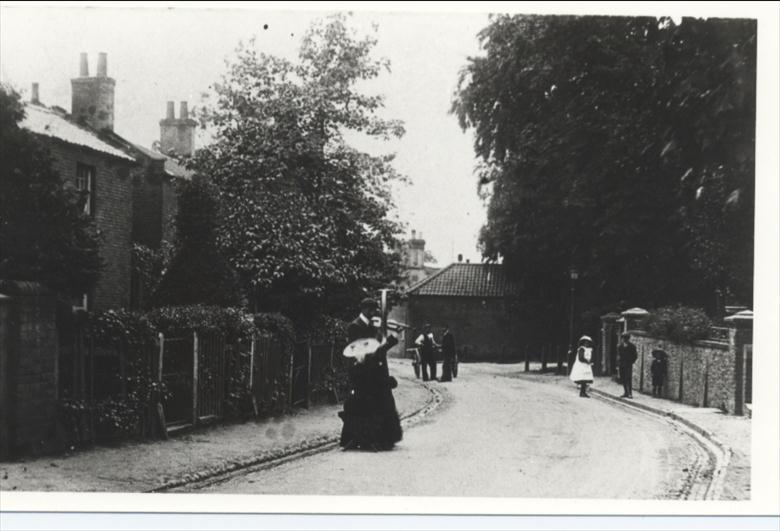 Photograph. Grammar School Road showing two buskers with violin and harp (North Walsham Archive).