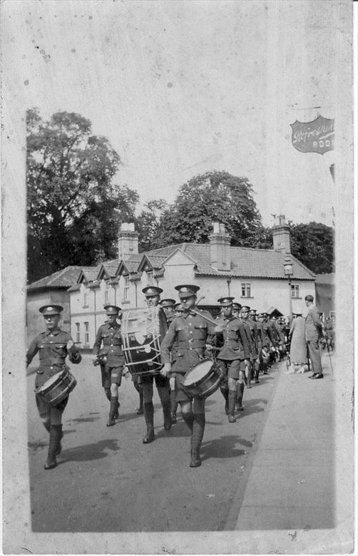 Photograph. Paston School Cadet Force, led by its band, marching along Norwich Road. Bull Inn in the background. (North Walsham Archive).